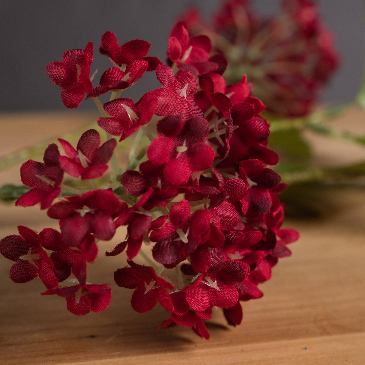 Close-up of red artificial viburnum flowers on a wooden surface