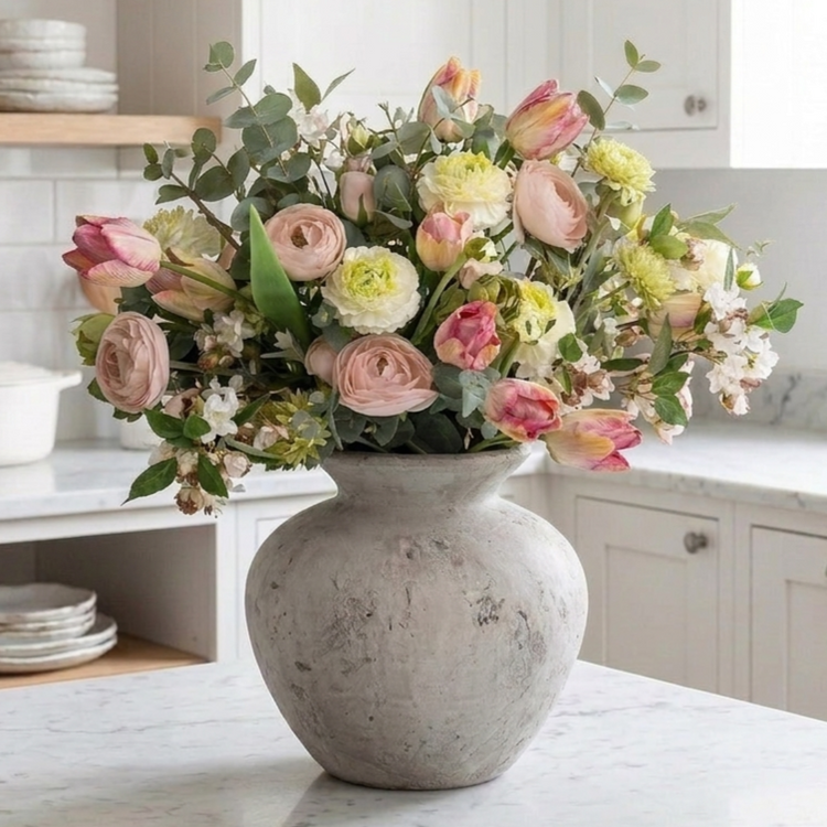 Faux floral arrangement with blush ranunculus and parrot tulips in a stone vase on a marble kitchen countertop - Artanna