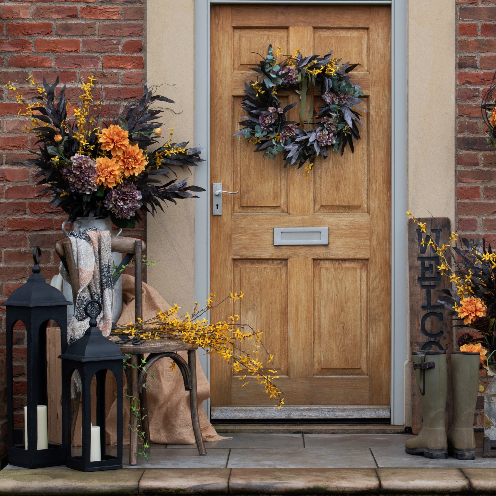 Decorative wreath on a wooden door with autumn-themed decorations outside.