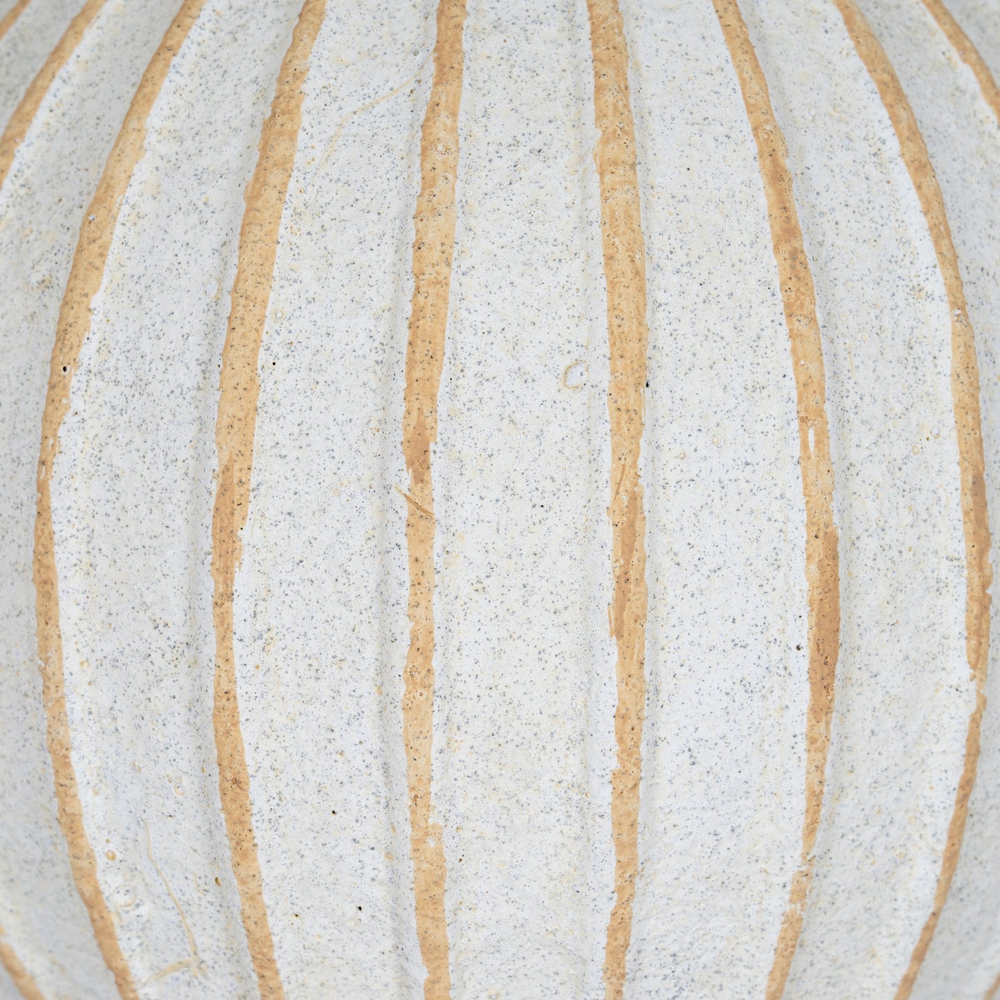 Close-up of a textured surface with horizontal beige stripes on a light gray background