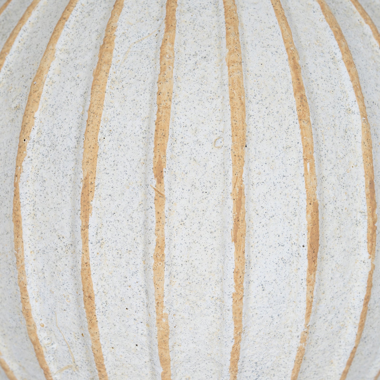 Close-up of a textured surface with horizontal beige stripes on a light gray background