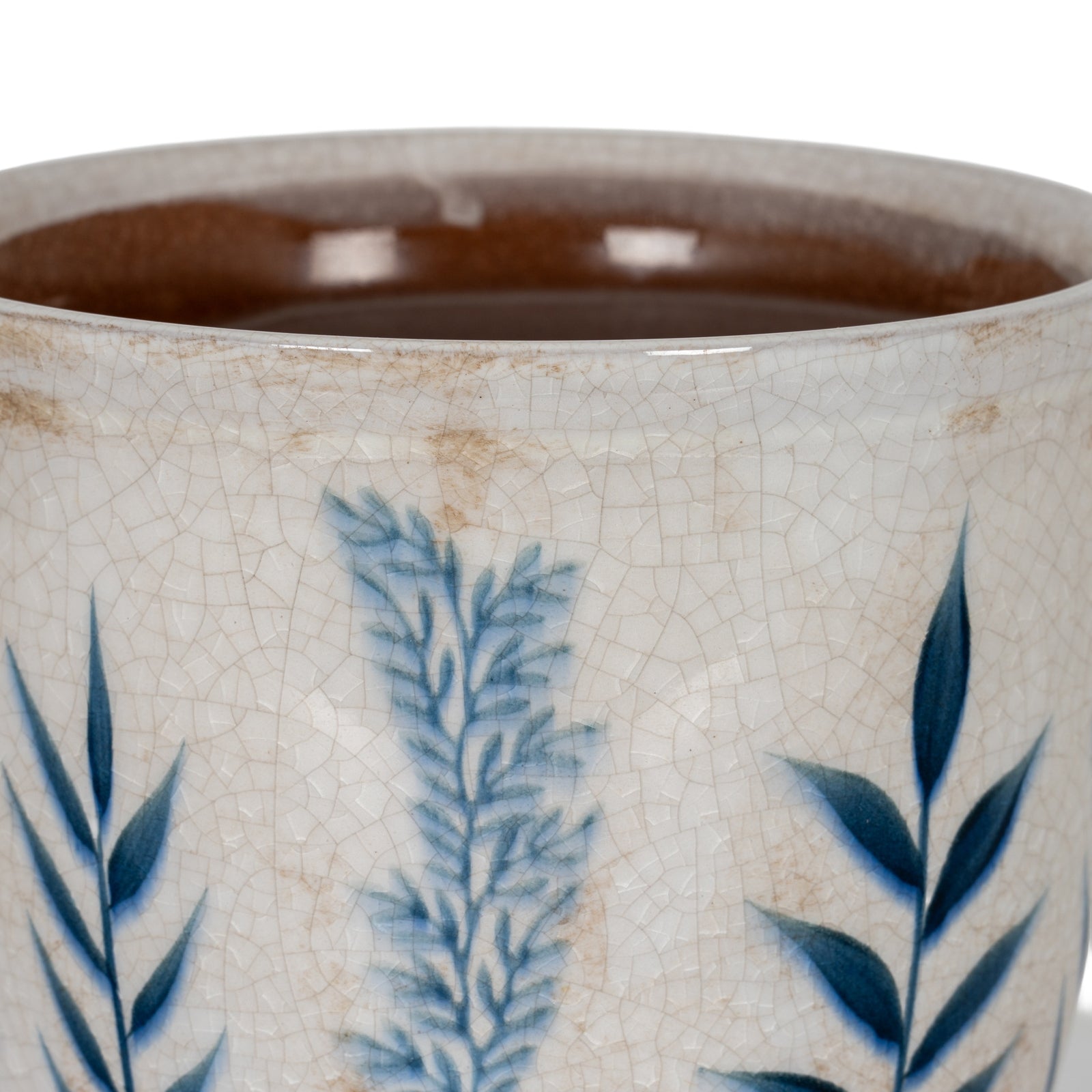 Close-up of a ceramic mug with blue leaf patterns on a white background