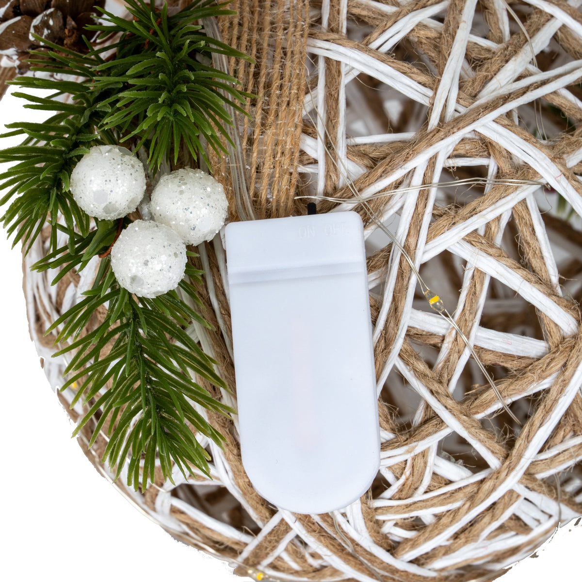 close up of led battery on a decorative wreath with greenery and white berries.