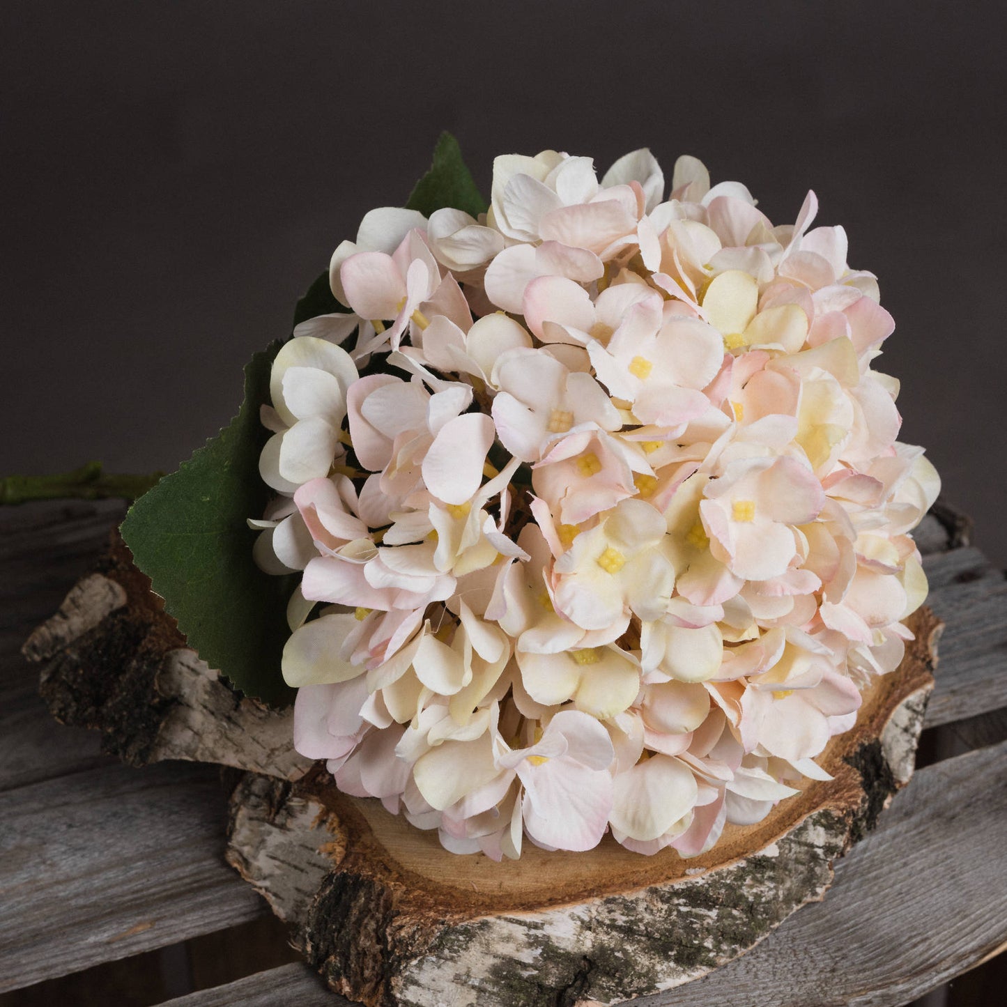 Bouquet of light pink and white flowers on a wooden surface with a dark background