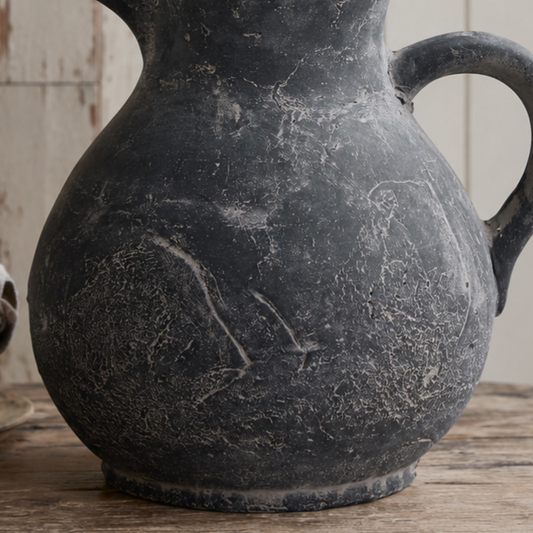 Black ceramic jug vase with engraved design on a wooden surface