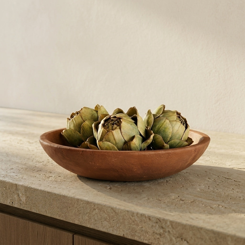 Bowl of artichokes on a stone surface with a neutral background