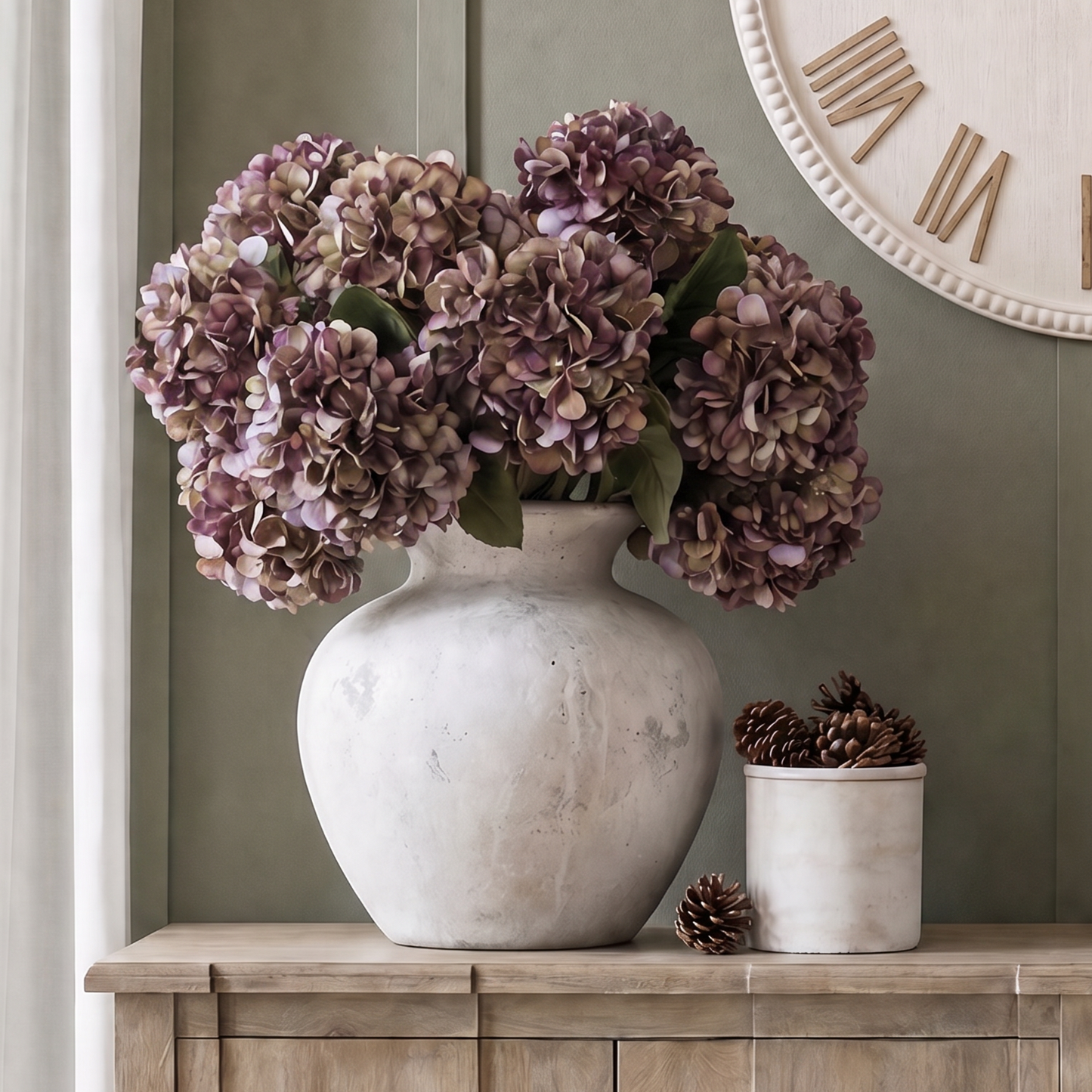Autumn burgundy artificial hydrangea stem with rich purple and green hues styled in a ceramic vase on a wood sideboard