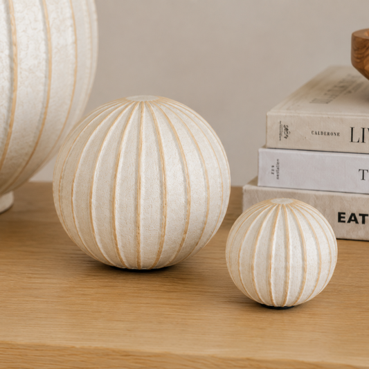 Decorative spherical ornaments on a wooden surface with books in the background