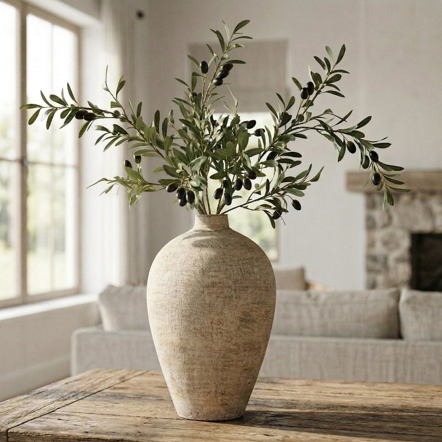 Decorative vase with olive branches on a wooden table in a living room setting