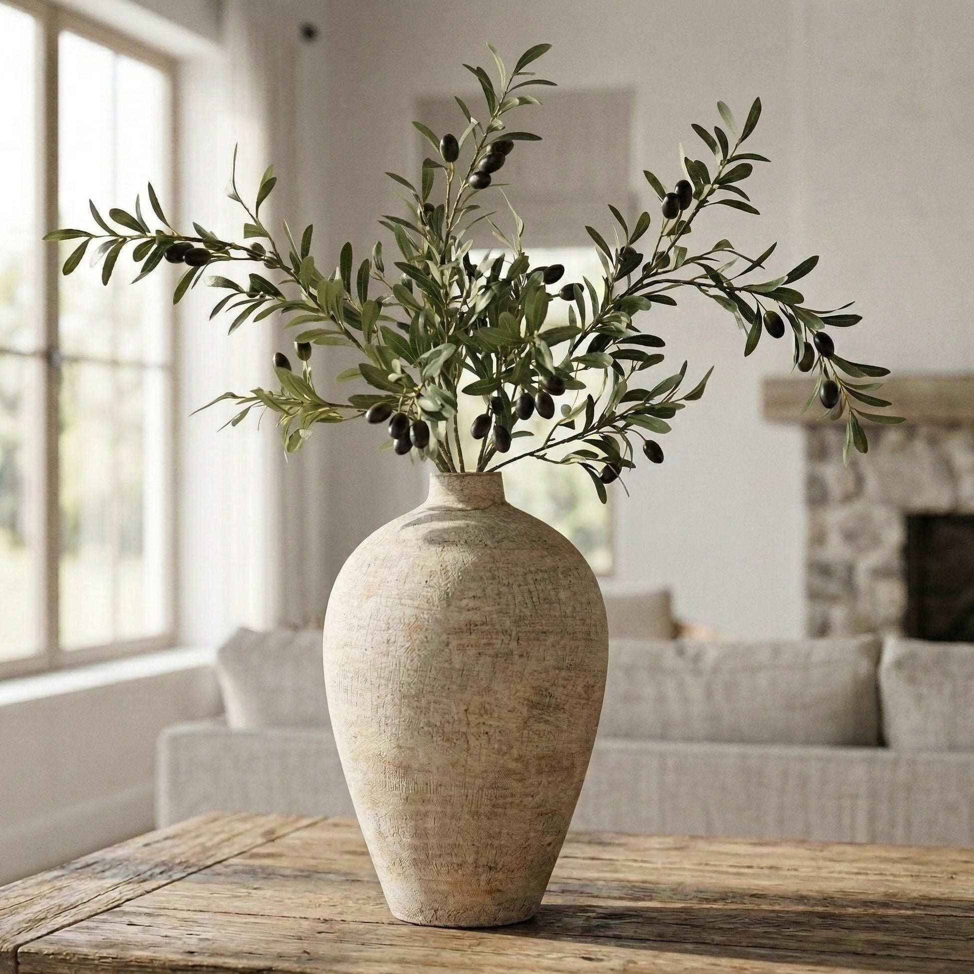 Decorative vase with olive branches on a wooden table in a living room setting