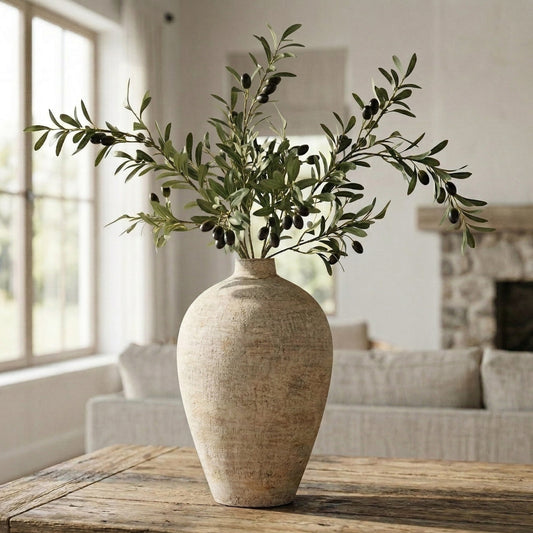Decorative vase with olive branches on a wooden table in a living room setting