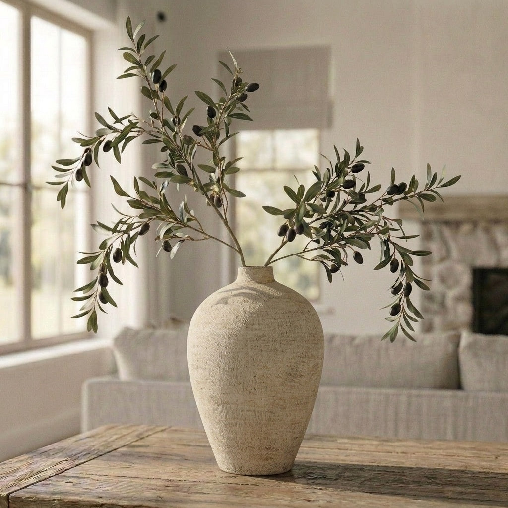Beige vase with olive branches on a wooden table in a living room setting