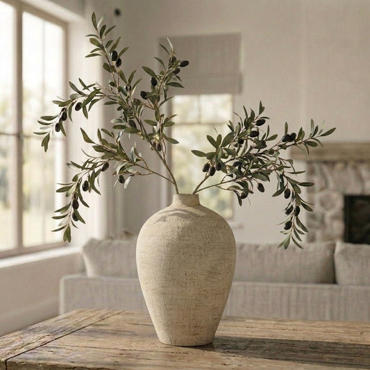 Beige vase with olive branches on a wooden table in a living room setting