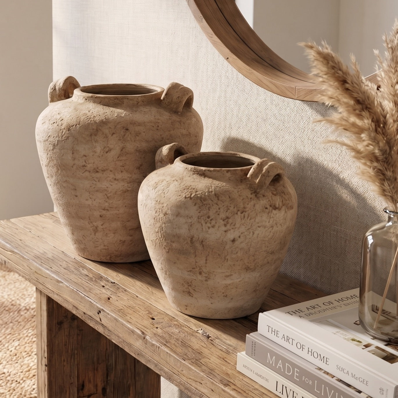 Two rustic urh vase pots on a rustic console table with books and a vase in the background.